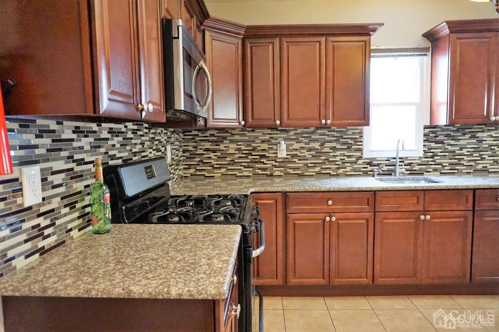 559 Johnstone Street Perth Amboy, NJ 08861 - Photo 11 of 24 a kitchen with granite countertop a sink a stove and cabinets