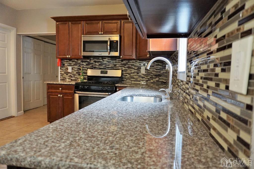 559 Johnstone Street Perth Amboy, NJ 08861 - Photo 13 of 24 a kitchen with stainless steel appliances granite countertop a stove a sink and a microwave