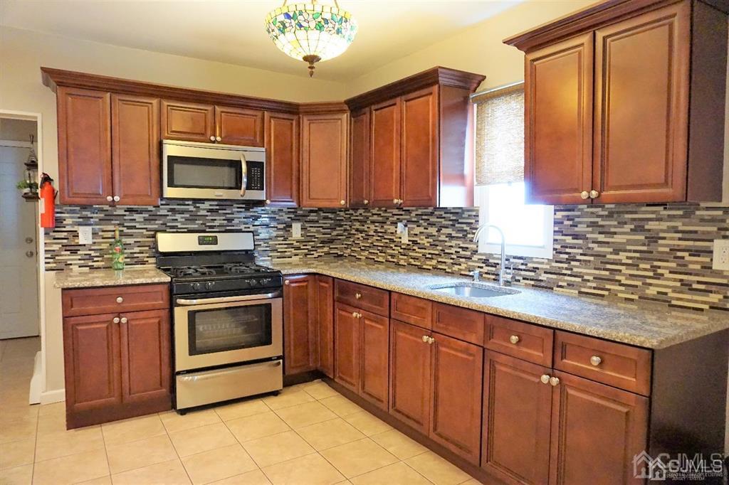559 Johnstone Street Perth Amboy, NJ 08861 - Photo 9 of 24 a kitchen with stainless steel appliances granite countertop a sink stove and microwave