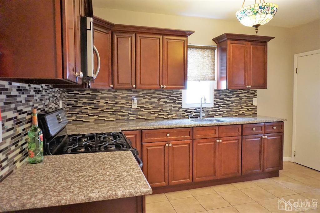 559 Johnstone Street Perth Amboy, NJ 08861 - Photo 10 of 24 a kitchen with stainless steel appliances granite countertop a stove a sink and a microwave