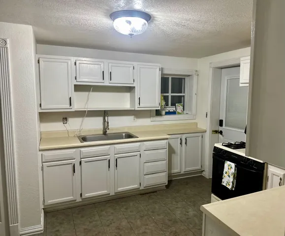 a kitchen with sink stove and cabinets