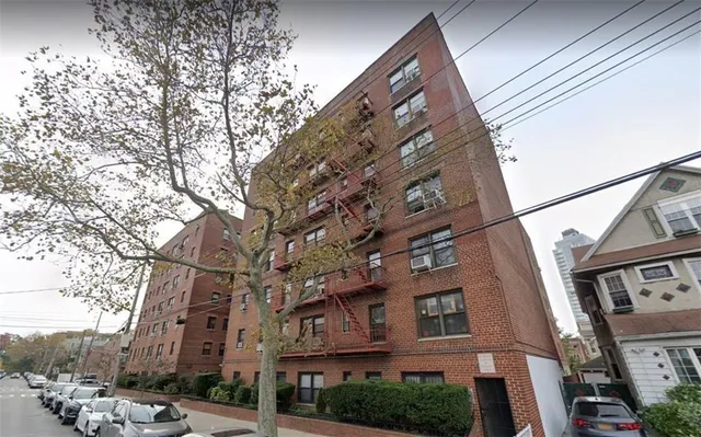 front view of a brick building with a lots of flower plants