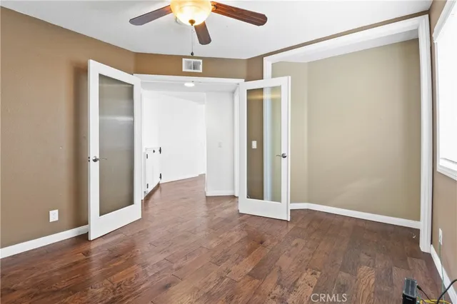 an empty room with wooden floor and a ceiling fan