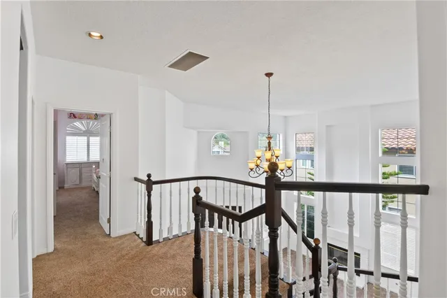 a view of a hallway with windows and chandelier