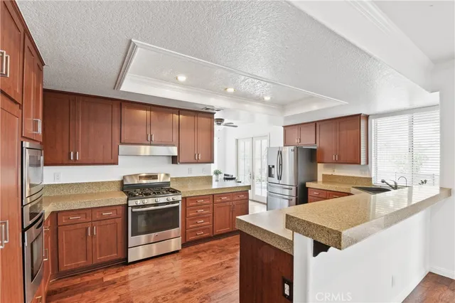 a kitchen with stainless steel appliances a sink a stove a refrigerator cabinets and a window