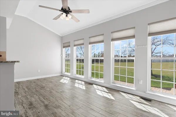 a view of an empty room with wooden floor fireplace and a window