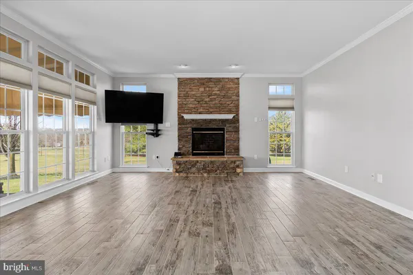 a view of an empty room with wooden floor and a chandelier