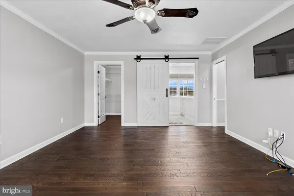 an empty room with windows and chandelier fan