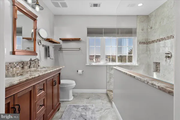 a bathroom with a granite countertop sink a toilet and a mirror