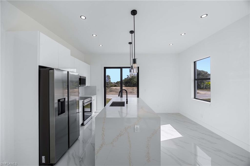 2700 49th Street Southwest Lehigh Acres, FL 33976 - Photo 13 of 24 Kitchen featuring modern cabinets, stainless steel appliances, recessed lighting, light marble finish flooring, and pendant lighting