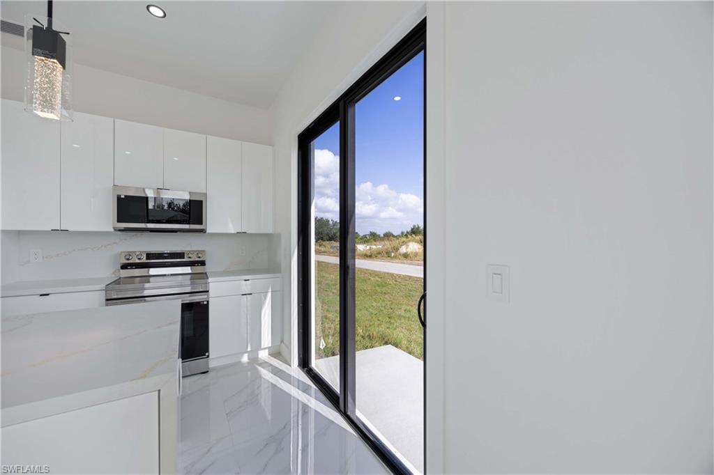 2700 49th Street Southwest Lehigh Acres, FL 33976 - Photo 16 of 24 Kitchen featuring white cabinetry, stainless steel appliances, modern cabinets, light marble finish flooring, and light stone counters