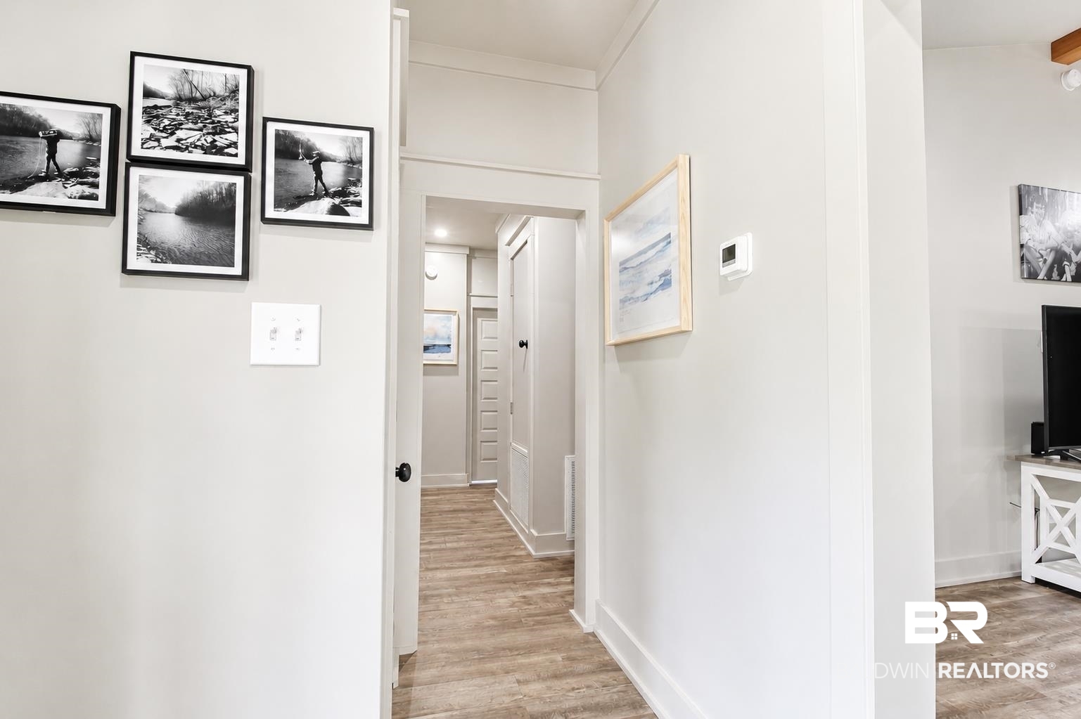 9825 Wolf Creek Ridge Elberta, AL 36530 - Photo 6 of 76 Hallway featuring wood-finish flooring, light gray walls, white baseboards, and a white interior door with black hardware