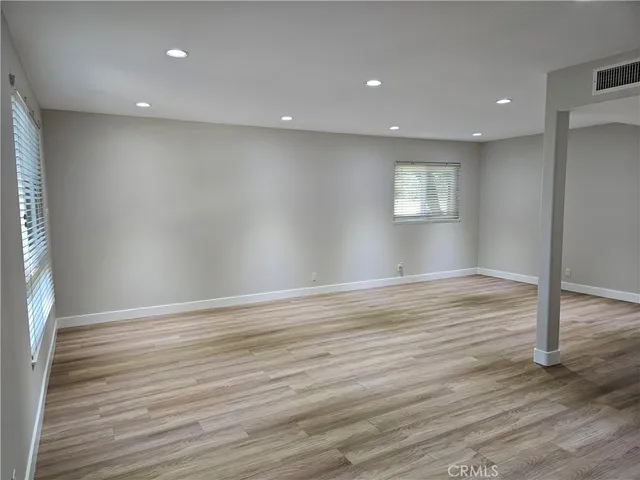 an empty room with wooden floor and window