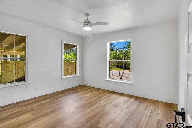 a view of an empty room with window and wooden floor