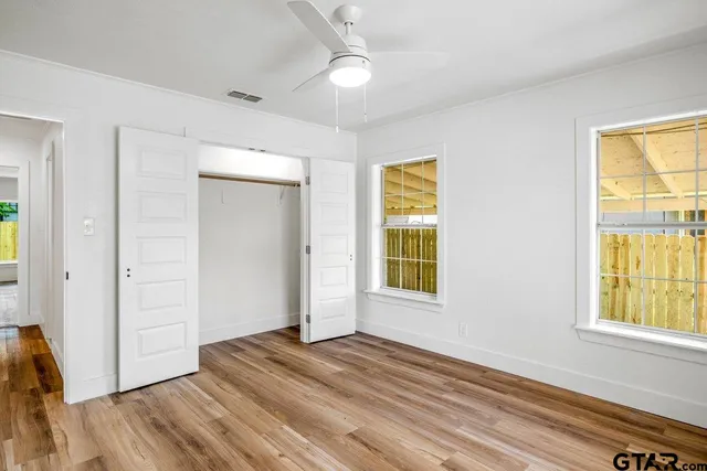 a view of empty room with wooden floor and fan