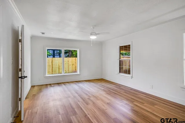 a view of an empty room with a window and wooden floor