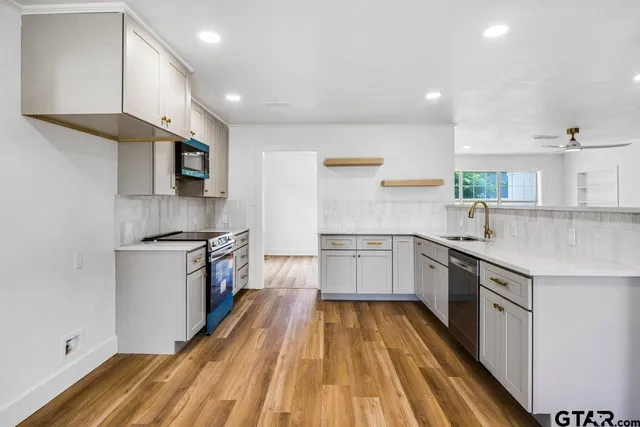 a kitchen with a sink a counter top space stainless steel appliances and cabinets