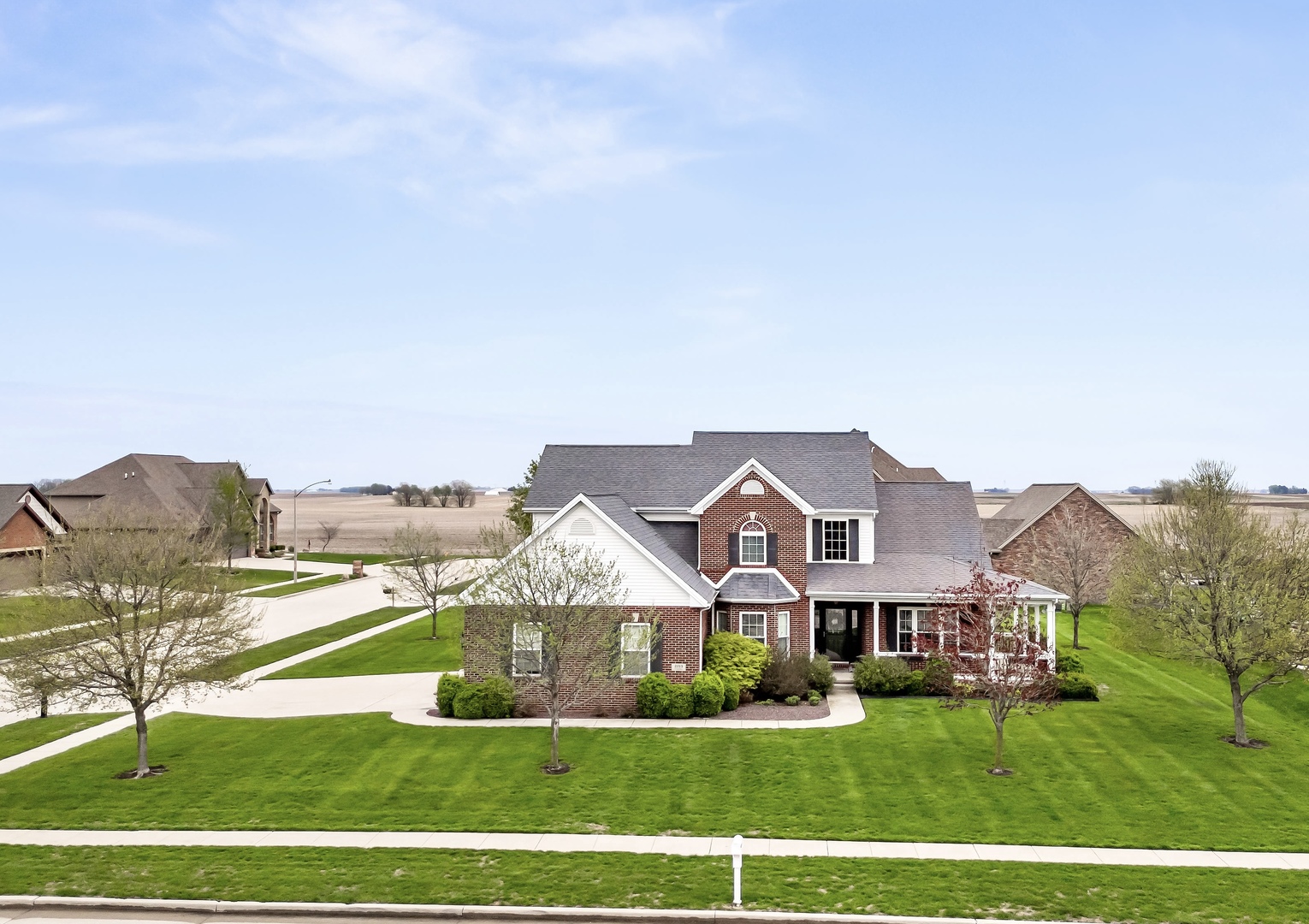 a view of a big house with a big yard and large trees