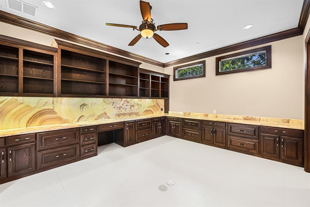 5821 Northaven Road Dallas, TX 75230 - Photo 28 of 40 Built-in dark wood cabinetry with integrated shelving, a desk area, and a striking stone backsplash