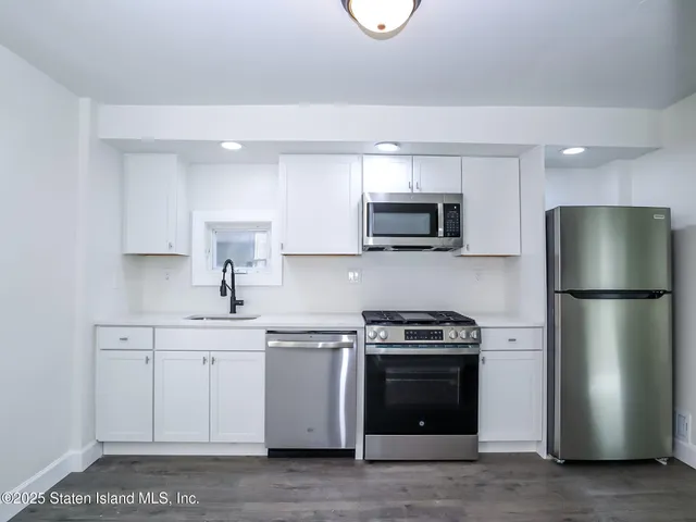 a kitchen with a sink a stove a refrigerator and white cabinets