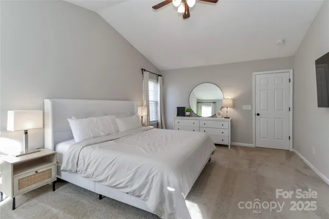 a spacious bedroom with a bed a chandelier with dresser and mirror