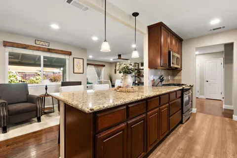 a bathroom with a granite countertop sink a large mirror and a wooden floors