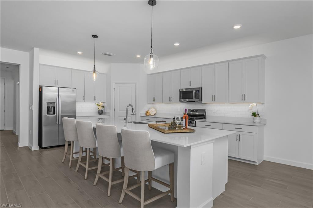 21094 Verawood Loop Estero, FL 33928 - Photo 10 of 49 a kitchen with stainless steel appliances kitchen island a table chairs refrigerator sink and cabinets
