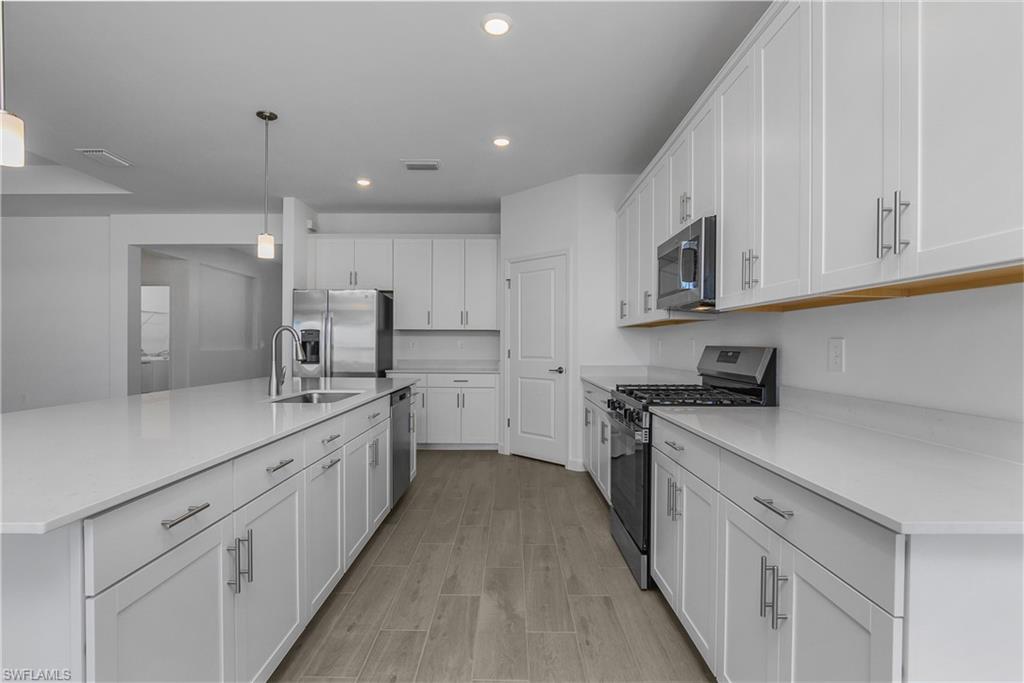 21094 Verawood Loop Estero, FL 33928 - Photo 7 of 49 a kitchen with kitchen island granite countertop lots of white stainless steel appliances cabinets and a sink