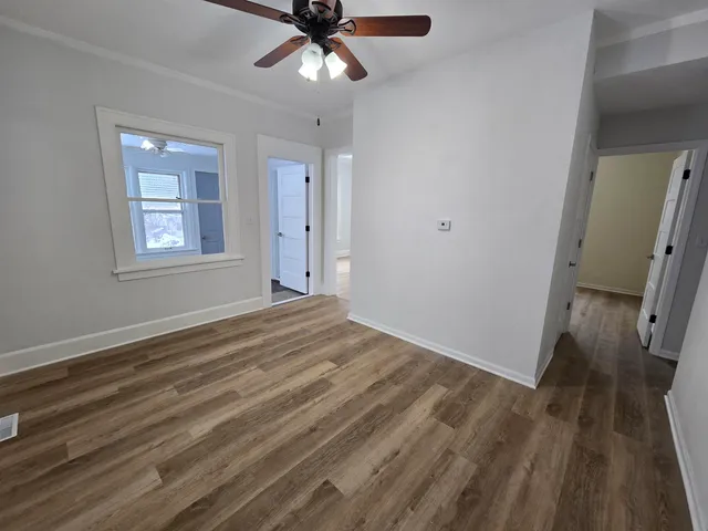 a view of empty room with wooden floor and fan