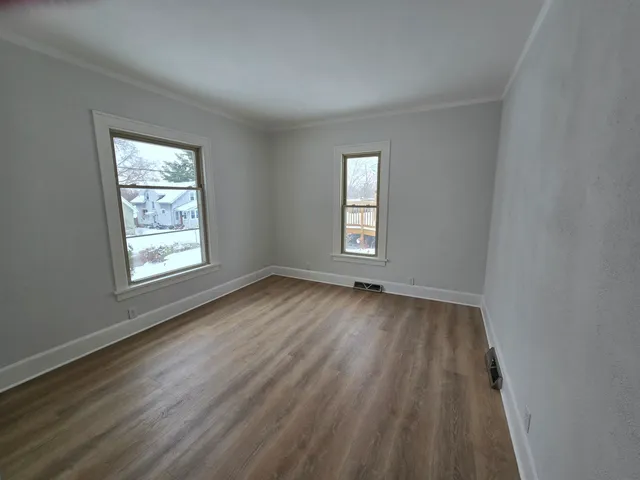 a view of an empty room with wooden floor and window