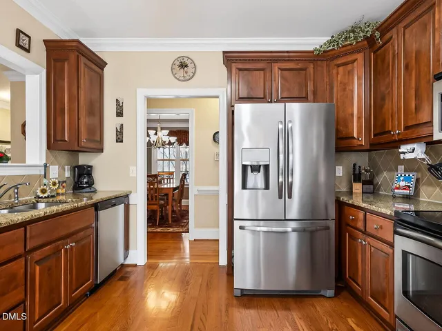 a kitchen with stainless steel appliances granite countertop a refrigerator stove and sink with wooden floor