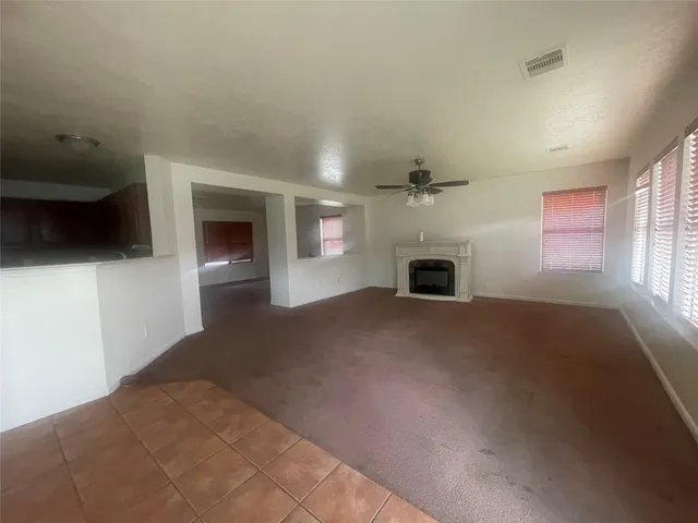 en empty room with windows and fireplace