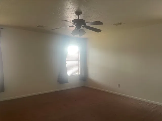 an empty room with a window and a fan