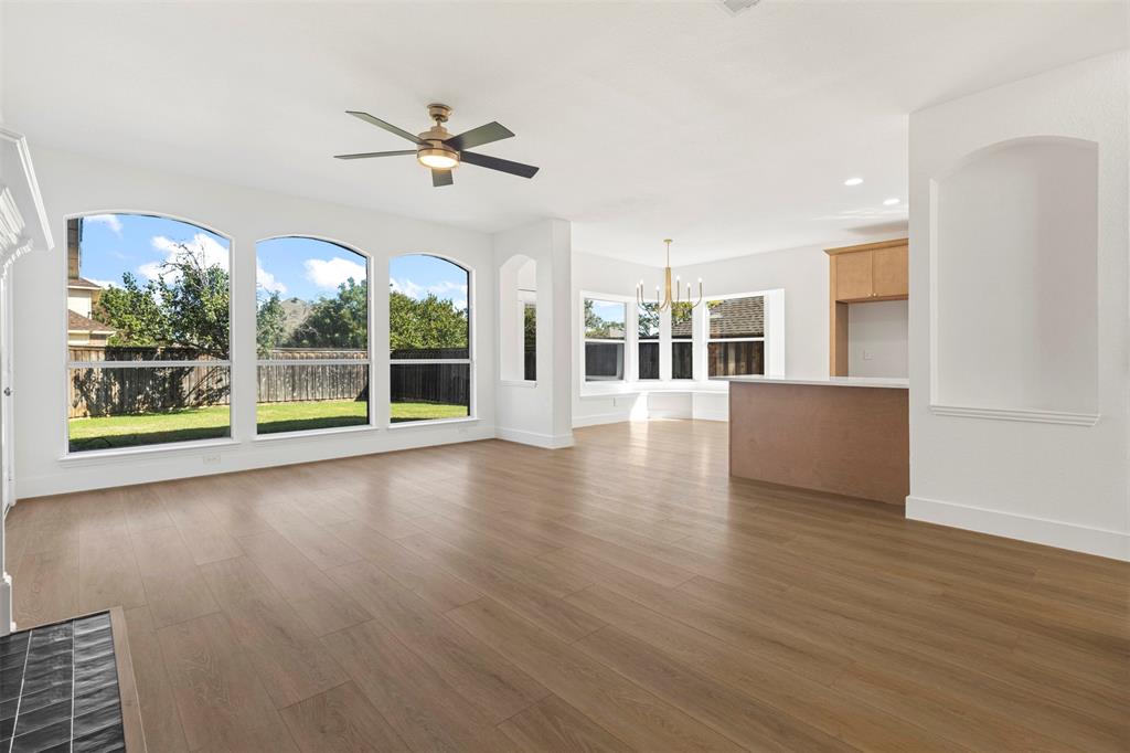 421 Ridge Meade Drive Lewisville, TX 75067 - Photo 13 of 36 a view of a livingroom with wooden floor a ceiling fan and windows