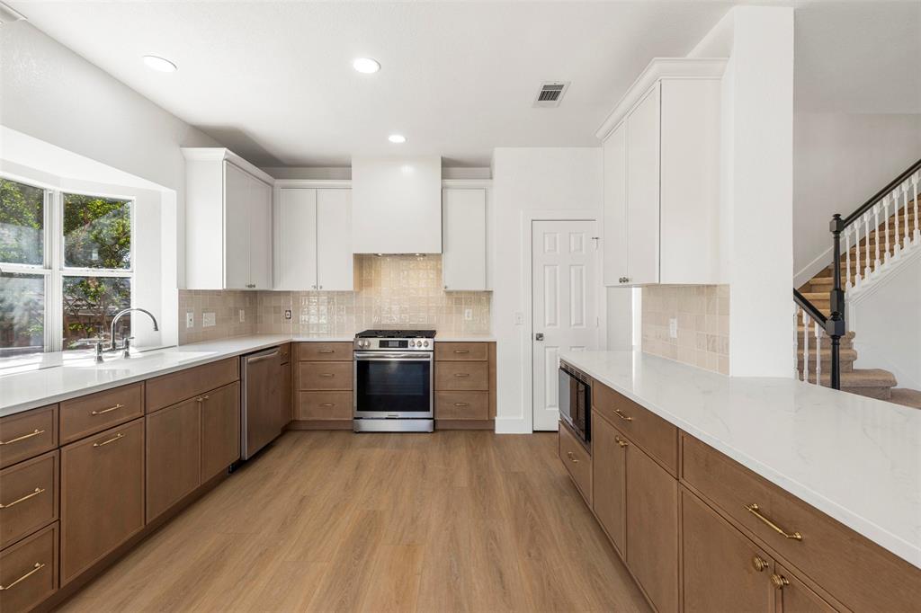 421 Ridge Meade Drive Lewisville, TX 75067 - Photo 3 of 36 a large kitchen with stainless steel appliances granite countertop a lot of counter space and wooden floors