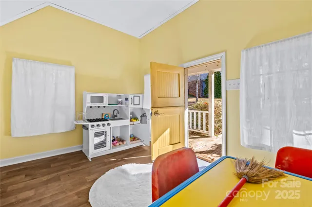 a living room with stainless steel appliances furniture windows and a kitchen view