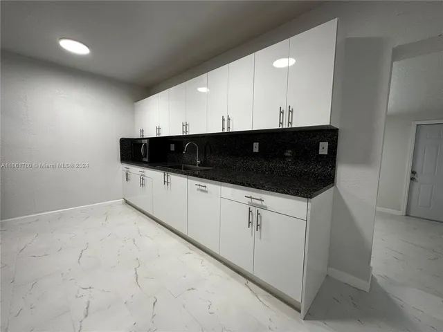 a kitchen with granite countertop white cabinets and sink