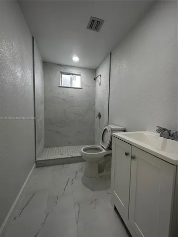 a bathroom with a granite countertop sink a toilet and shower