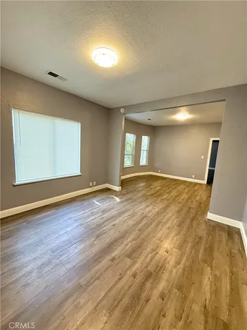 a view of an empty room with wooden floor and a window
