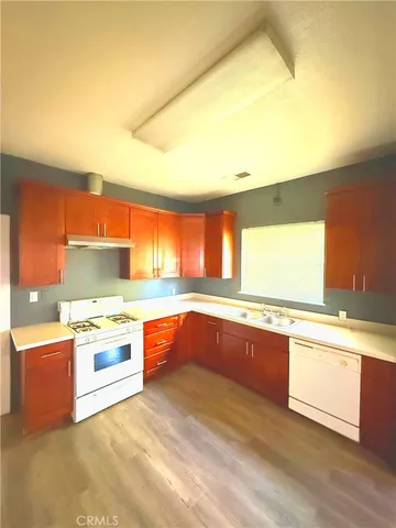 a kitchen with stainless steel appliances granite countertop a sink and cabinets with wooden floor