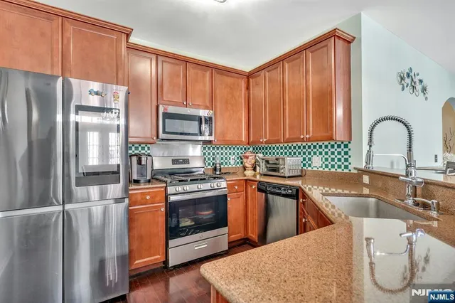 a kitchen with stainless steel appliances granite countertop a refrigerator sink and stove