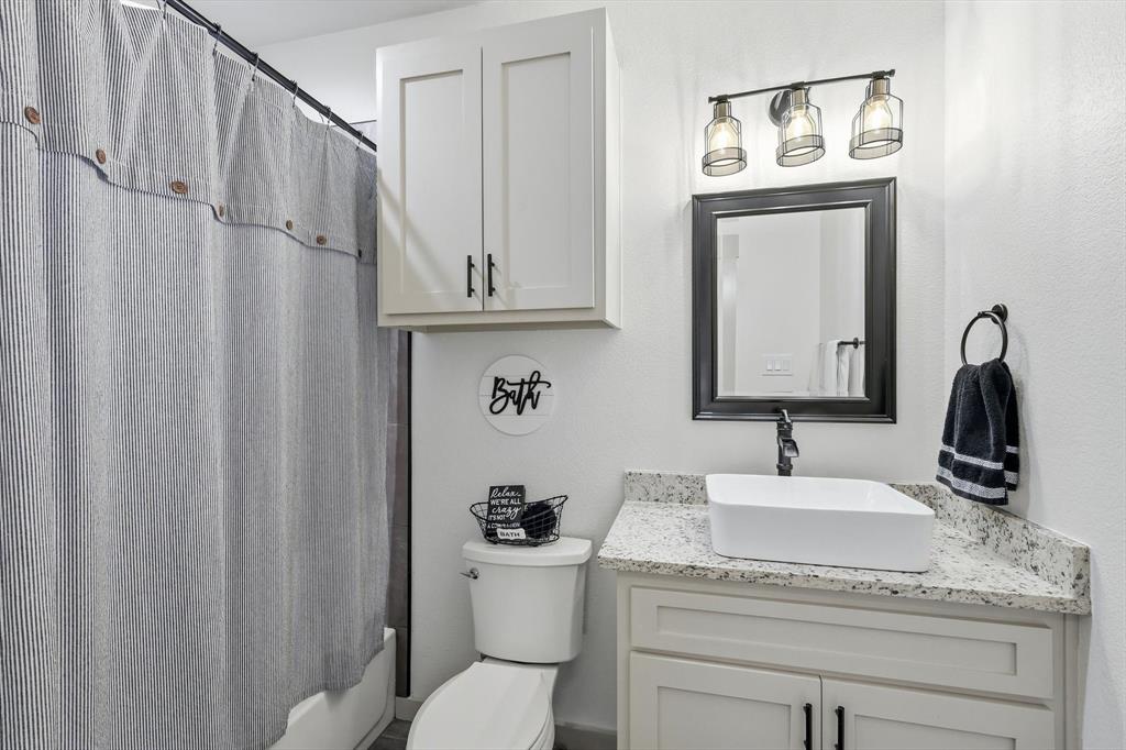 6020 Honeysuckle Road Midlothian, TX 76065 - Photo 23 of 39 Bathroom featuring a vessel sink, stone-finish countertop, and white shaker-style cabinetry