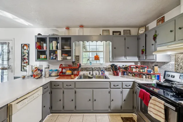 a utility room with stainless steel appliances granite countertop a sink stove and cabinets