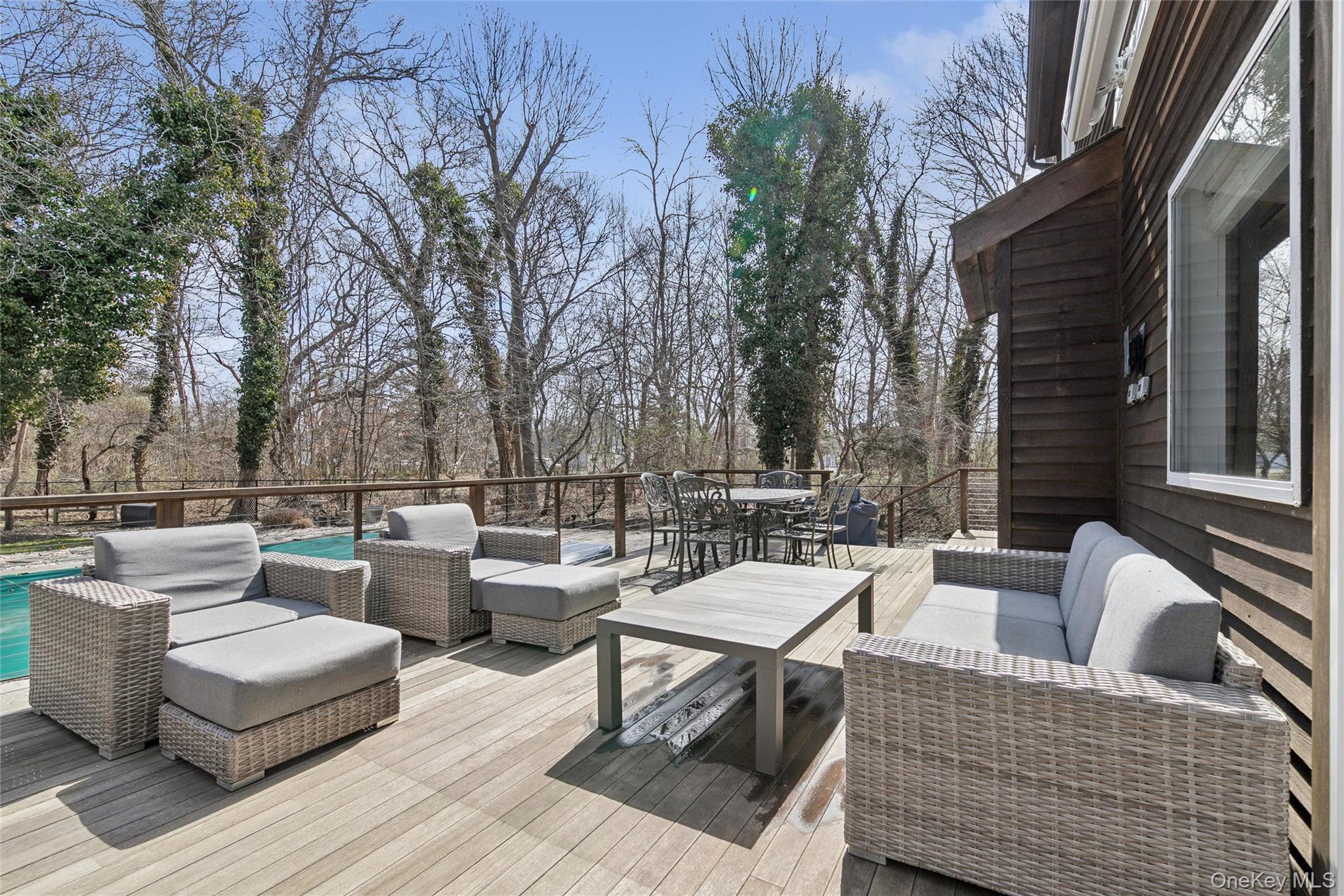 131 Lewis Road East Quogue, NY 11942 - Photo 19 of 25 a view of a patio with couches and a table and chairs with wooden floor and fence