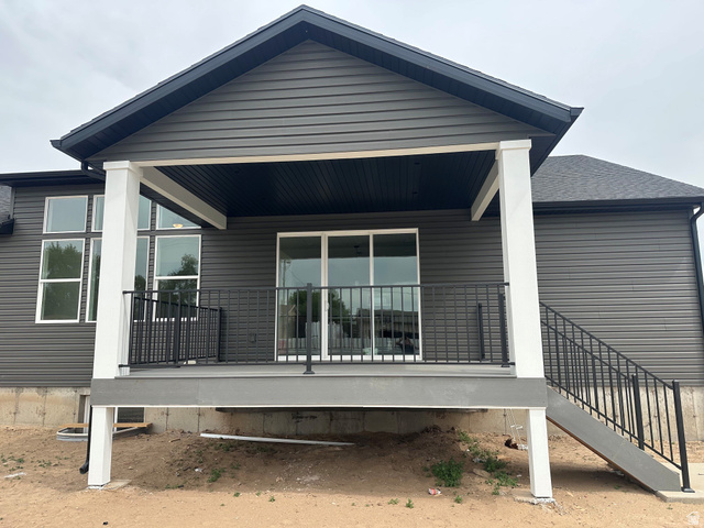 3839 West 825 North, Unit WF18 West Point, UT 84015 - Photo 22 of 22 Covered patio featuring a sliding glass door, black metal railing, composite decking, and exterior stairs