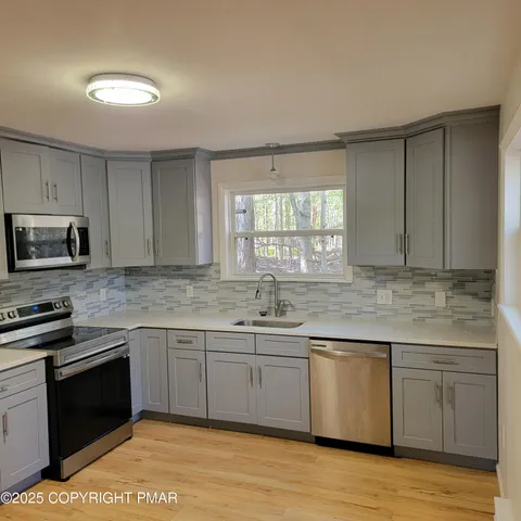 a kitchen with stainless steel appliances granite countertop a sink cabinets and wooden floor