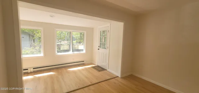 a view of an empty room with wooden floor and a window