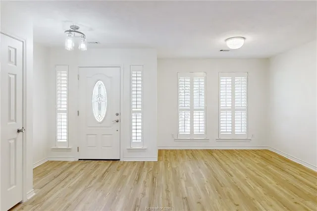 an empty room with wooden floor and window
