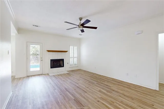 an empty room with wooden floor a fireplace a ceiling fan and wooden floor