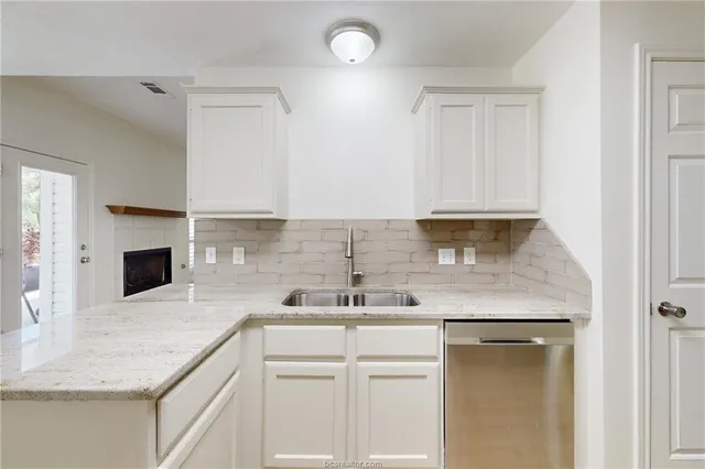 a kitchen with a sink dishwasher a stove and a microwave oven with white cabinets